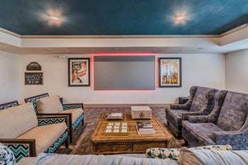 A living room with a couch, a coffee table, and a neon light on the wall.